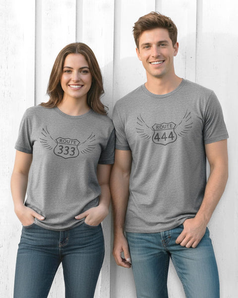 Woman wearing a heather gray unisex T‑shirt with a vintage 333 angel number design, alongside a man wearing a heather gray unisex T‑shirt with a vintage 444 angel number design.